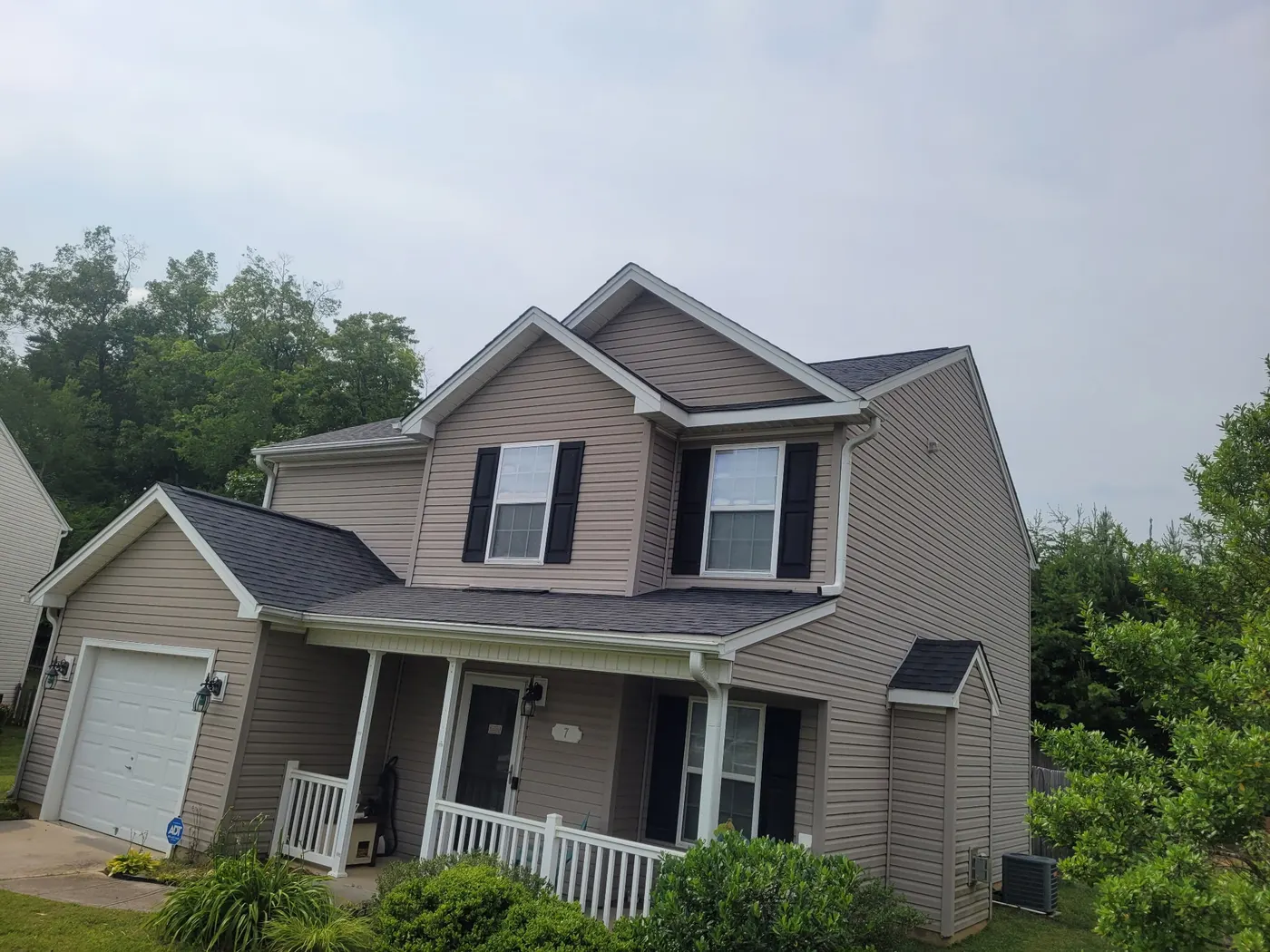 Tan two story home with a new black shingle roof